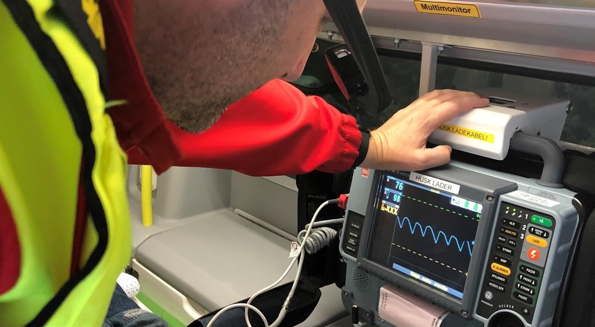 Ambulansepersonell som ser på målingar frå ein pasient i ambulansen
