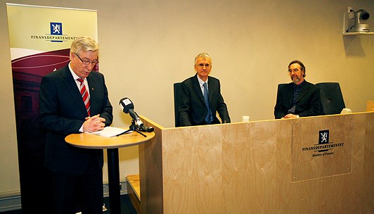 Ruhtadanministtar Sigbjørn Johnsen giitá OECD Patrick Lenain ja Paul O’Brien raporttas, maid soai geigiiga. Govven: Tor Martin Bærum/Ruhtadandepartemeanta