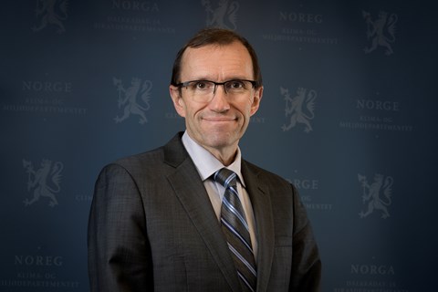 Utenriksminister Espen Barth Eide smilende i mørk dress med blå bakgrunn