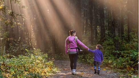 Kvinne og barn i skogen, lys skinner gjennom