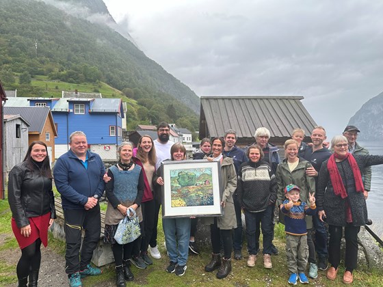 Fleire personar. Dei er vinnarar av den nasjonale kulturlandskapsprisen. Dei står framføre Aurlandsfjorden i bygda Undredal. Det er skodde over fjorden.