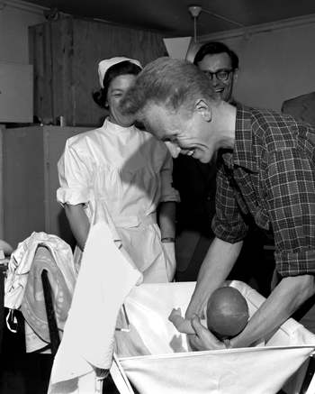 Figur 2.3 Oslo 1956. Pappa-kurs. Oslo Røde Kors med kurs i spebarnstell for vordende unge fedre. Pappa lærer grepet. Frithjof Spalder kastet jakka og brettet opp ermene for å ha fritt armslag mens den vanskelige badingen pågikk i stellebordet