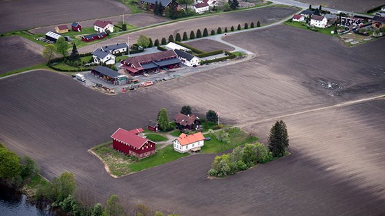 Gård i nypløyd åkerlandskap.