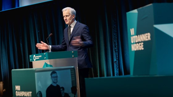 Jonas Gahr Støre står ved en talerstol og gestikulerer med armene mens han snakker.