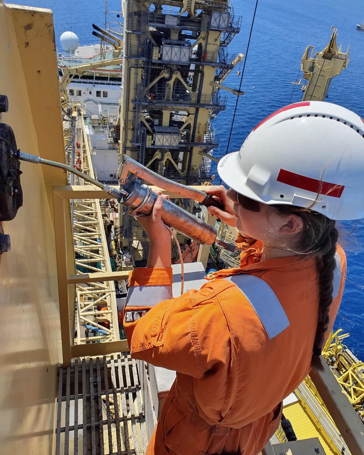 Woman doing outdoor maintenance work at a shipyard.