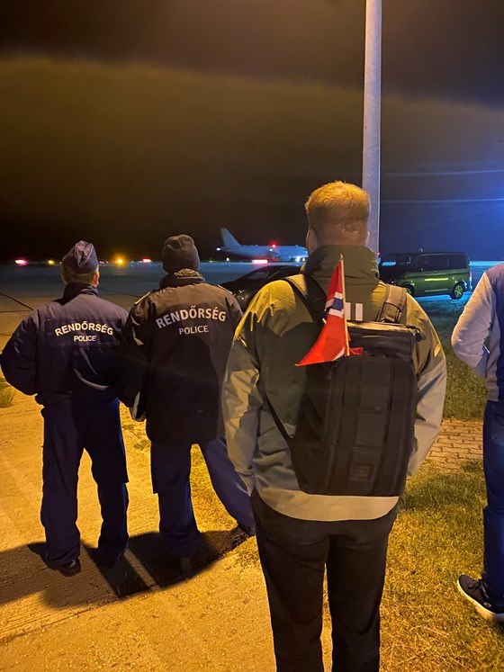 bilde av person med norsk flagg i sekken som ser på et fly