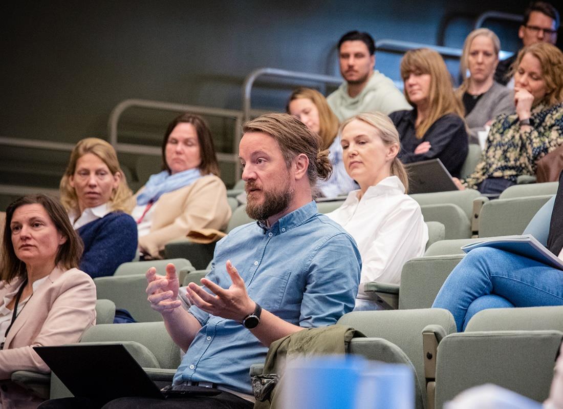 Oversiktsbilde over publikum i salen. Mannen i midten har ordet, og gestikulerer mens han snakker. Foto: Thorbjørn Helin