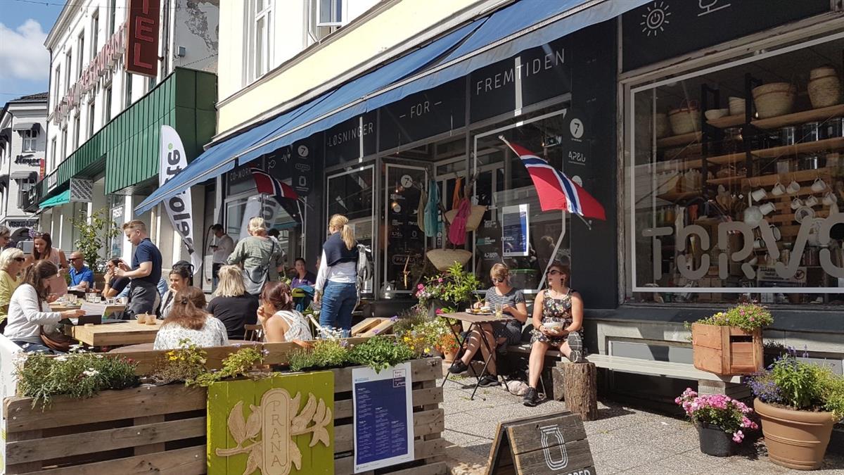 Blomster, bord og folk som sitter utenfor co-workinghus i sentrum