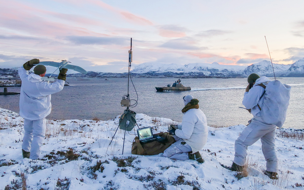 Figur 12.12 For å oppnå best mulig forsvarsevne må Forsvarets ressurser kunne samvirke. Samband og data-protokoller må derfor kunne fungere på tvers av forsvarsgrenene på lavest mulig nivå. Her øver soldater fra grensevakten sammen med en ubåt og en korvett fra ...