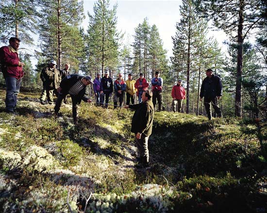 Figur 3.2 Skogeiere og skogtakstmenn lærer om kulturminner og
kulturmiljøer. Her studerer de en dyregrav som er en type
kulturminne man ofte finner i skogen – når man
vet hvordan de ser ut.