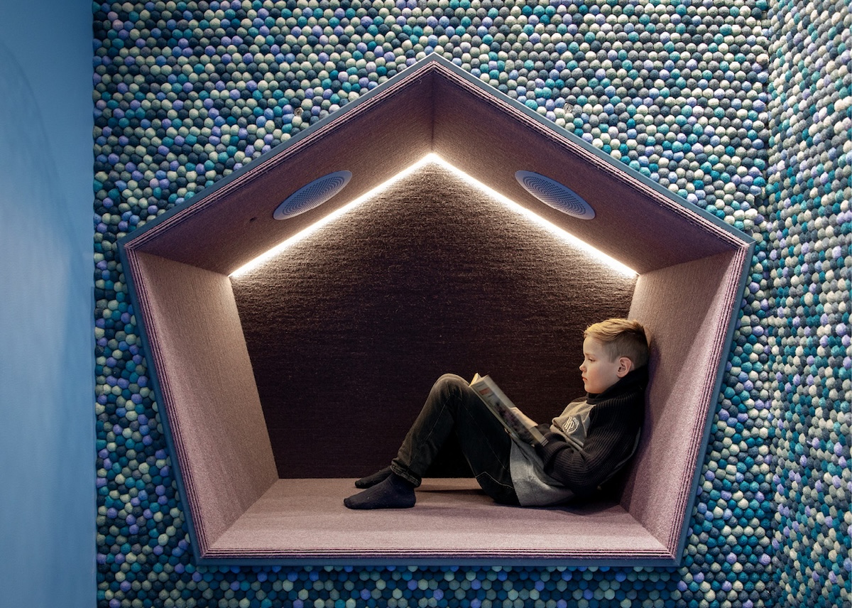 Ett barn leser bok i en "lesehule" i et bibliotek