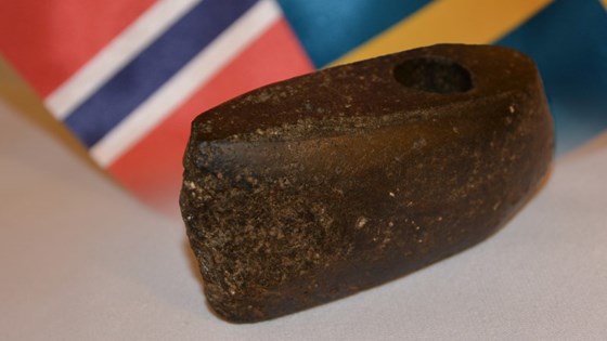 Bilde av øksehodet med norsk og svensk flagg i bakgrunnen.