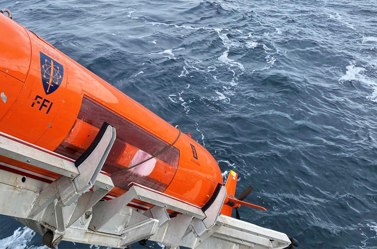 Foto viser HUGIN i ferd med å tas opp fra sjøen etter et oppdrag. HUGIN er en AUV. Hav med bølger.