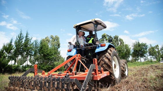 Bilde av utviklingsminister Anne Beathe Kristiansen Tvinnereim i en traktor på jorde i Afrika