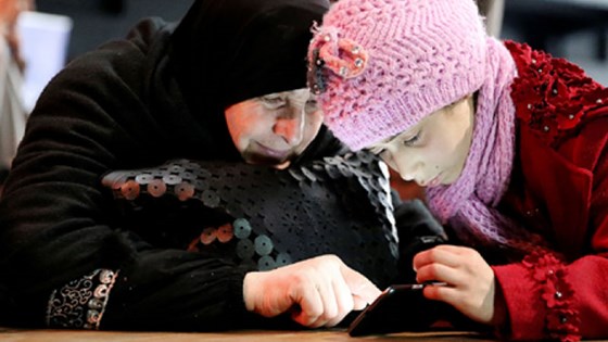 Syrian refugees trying out a mobile game designed to help children who are not attending school to learn to read. Norway has supported the development of two Arabic-language mobile learning apps in cooperation with NTNU, mobile telephony operators, game developers and others. Credit: Marit Hverven, Norad