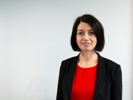 Portettbilde av Guro Angell Gimse, mot grå bakvegg