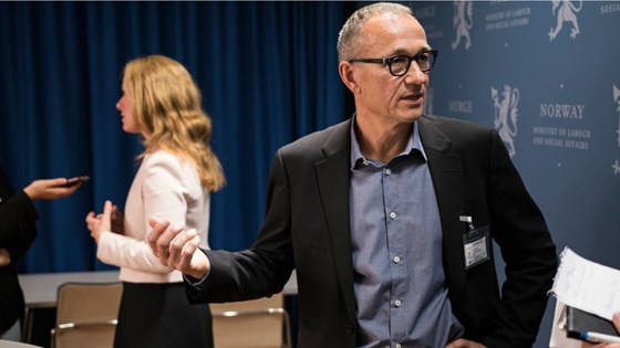 Samvittighetsutvalgets leder Bjørn K. Myskja i forgrunnen. Arbeids- og sosialminister Anniken Hauglie i bakgrunnen mens hun intervjues.