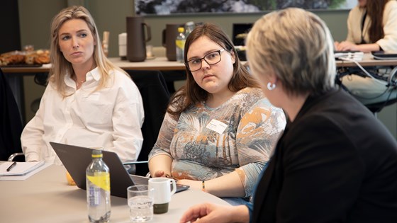 Arbeids- og inkluderingsministeren sitter rundt et bord og ser på landsleder i Mental Helse Ungdom Martine Antonsen og Maren Fuglesang i Unge funksjonshemmede