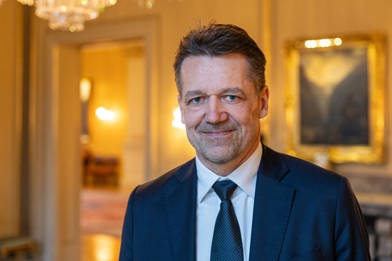 Mann i blå dress står i et flott rom.