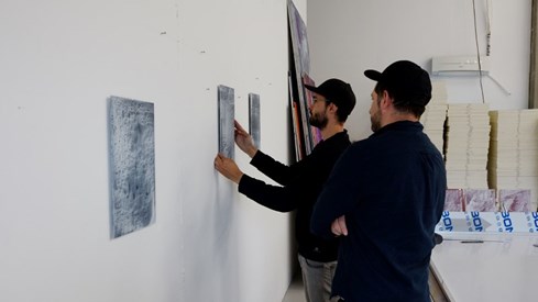 Kunstneren Javier Barrios. Foto: Marta Anna Løvberg / Kulturrådet Kunstneren Javier Barrios og en annen mann henger opp et kunstverk på veggen.