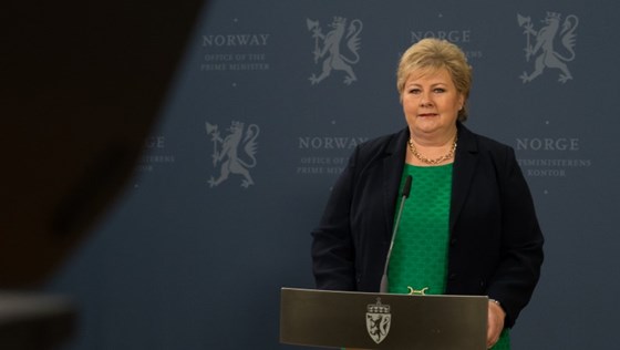 Statsminister Erna Solberg står bak en talestol på Statsministerens kontor