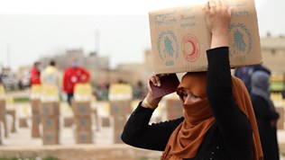 A woman collects food in Deir Hafer, 60 km from Aleppo in Syria. WFP is working with the Syrian Arab Red Crescent to distribute food to the most vulnerable. Credit: WFP/Khudr Alissa A woman collects food in Deir Hafer, 60 km from Aleppo in Syria. WFP is working with the Syrian Arab Red Crescent to distribute food to the most vulnerable.