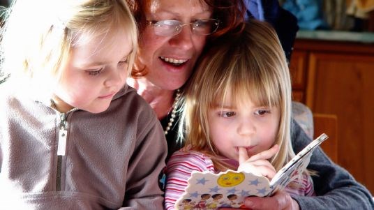 Voksen leser bok for to små barn